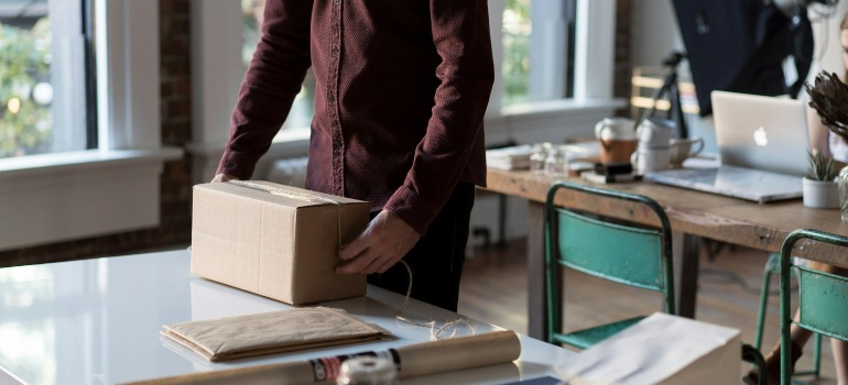 Person holding a cardboard box on a table