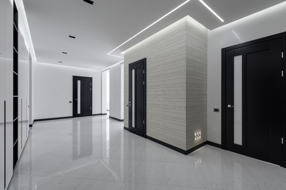 A white hall with black colored doors in LED light