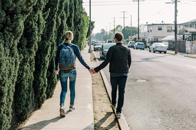 A couple holding hands and walking down a suburban street, exploring their new neighborhood.