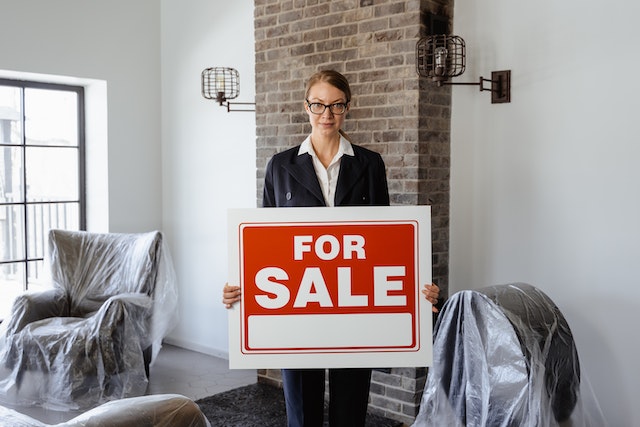 A real estate agent holding a for-sale sign