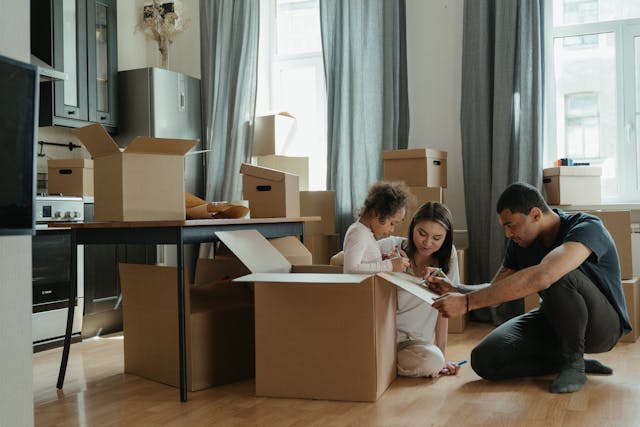 A family of three unpacking boxes in their new home.